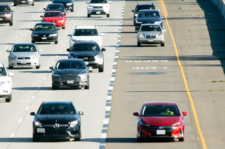 Three lanes of cars driving on a highway in traffic